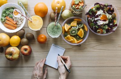 crop-hands-writing-near-healthy-food